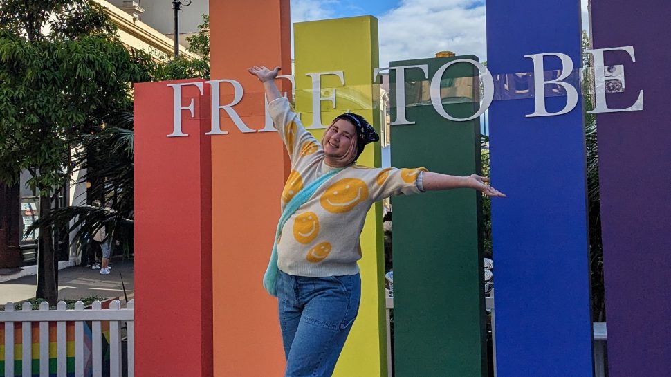Connor O’Rourke happily poses in front of rainbow sign at World Pride in 2023.