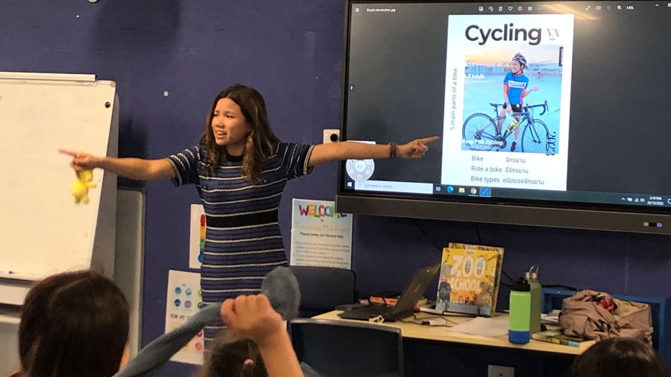 Woman teaching bicycle safety to a group of children.